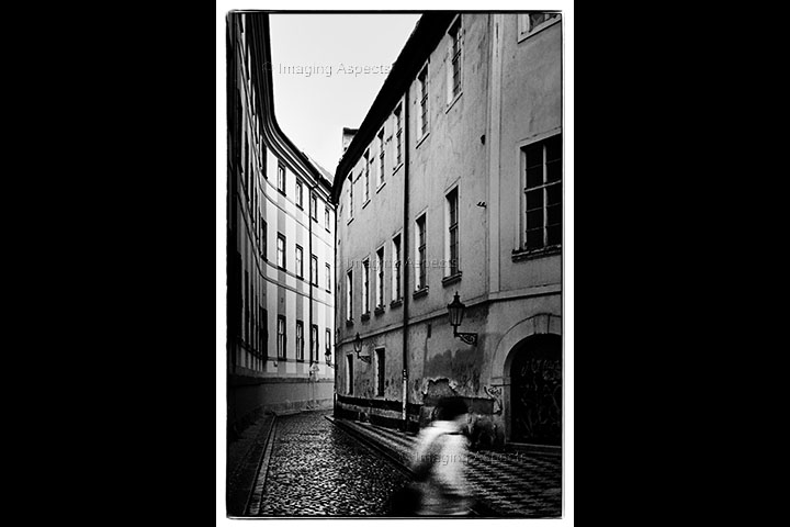 A young man crosses a back street in the old town of Prague, Czech Republic.