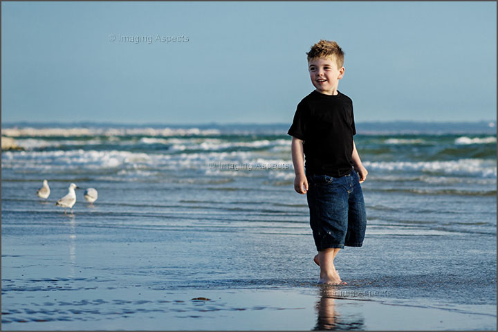 Young boy plays on the sandbank during low tide at Mentone Beach, Victoria.